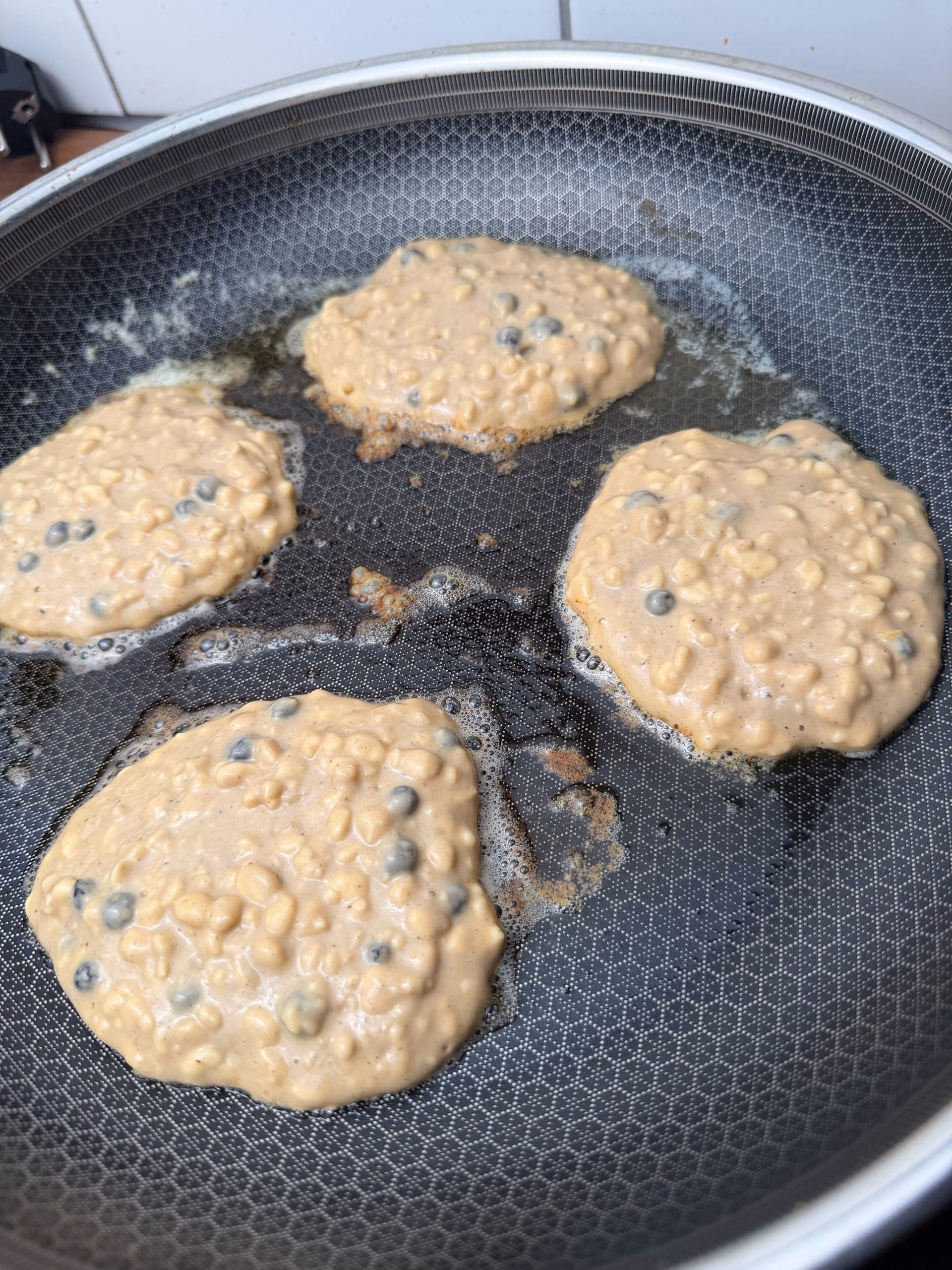 Vier Pancakes braten in einer beschichteten Pfanne