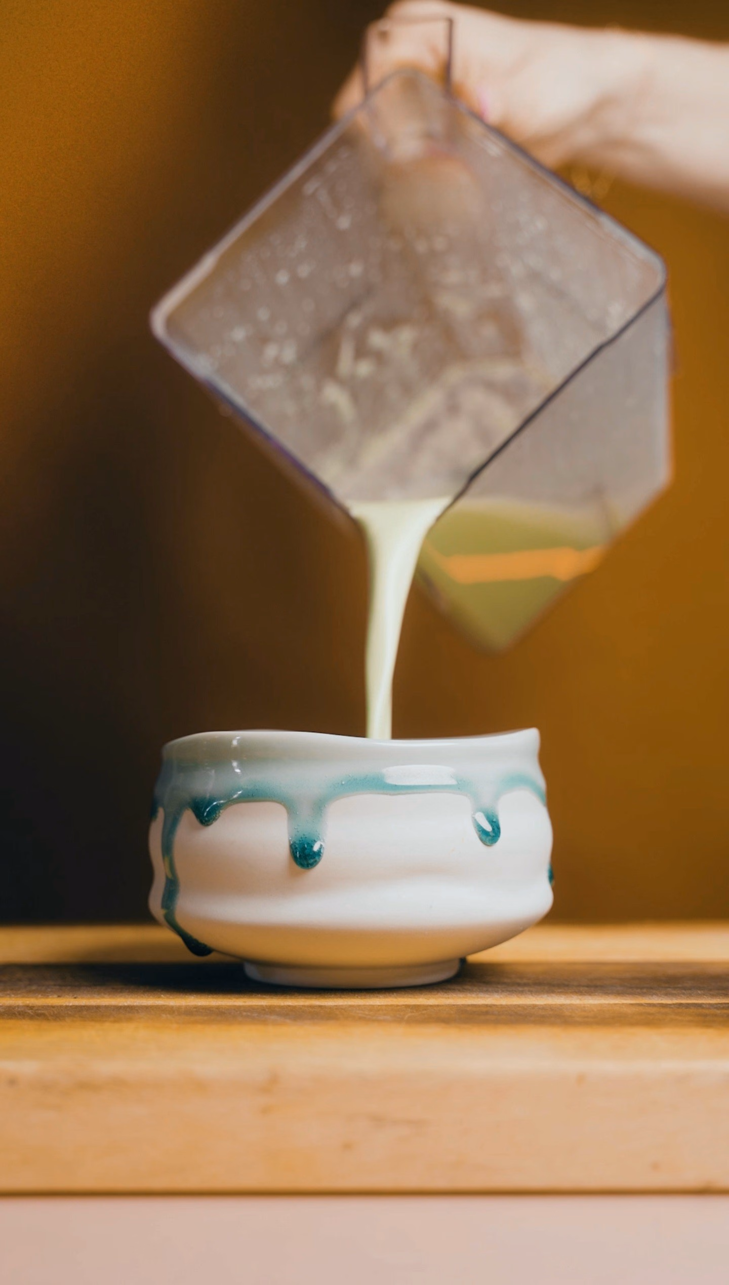 Cremiger Matcha wird aus einer Karaffe in eine Tasse gegossen