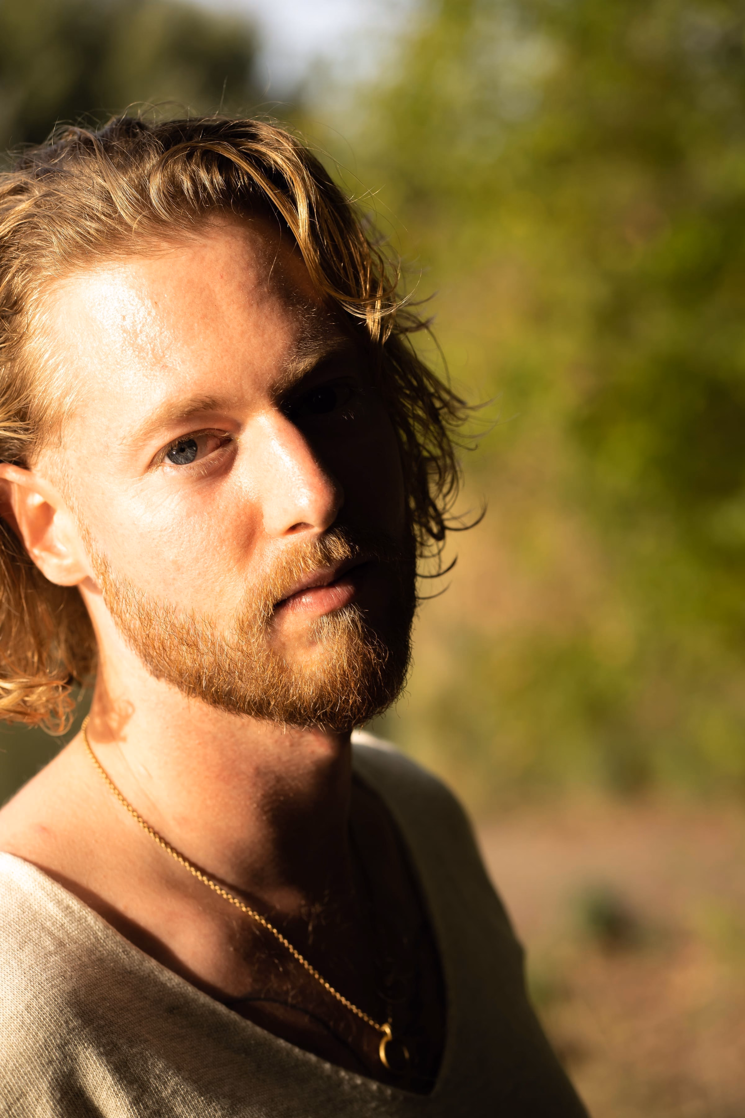 Portraet von Benjamin Weidig im Freien vor gruenem Hintergrund