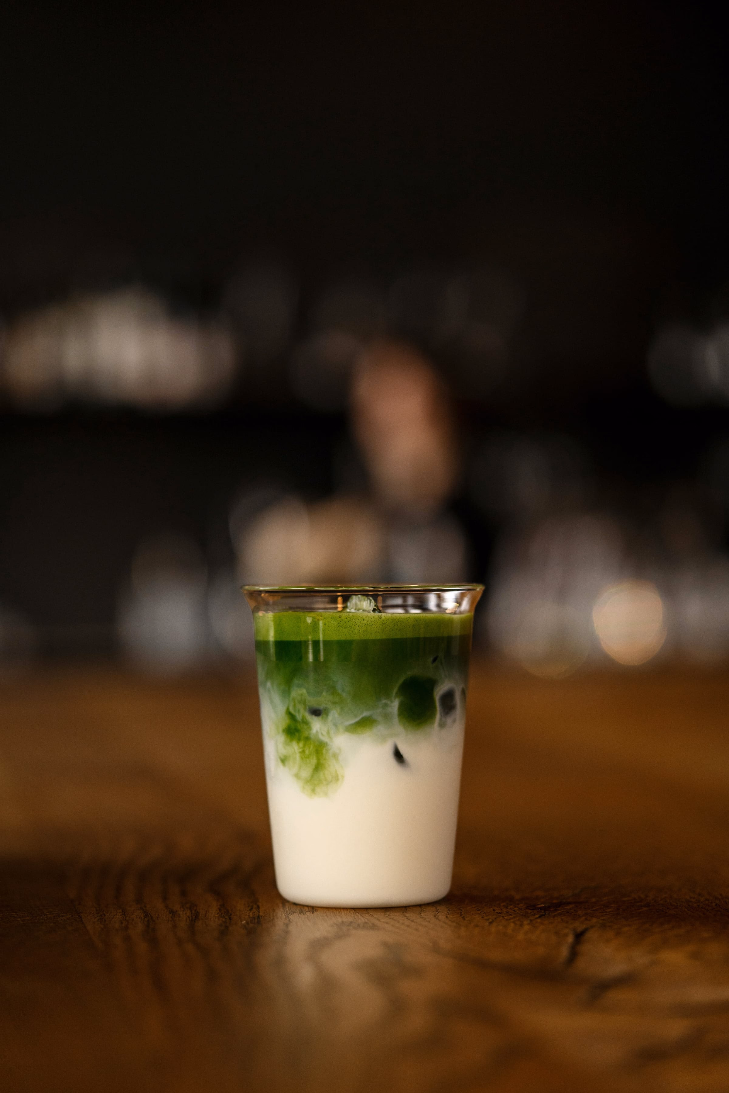 Gruener Matcha-Drink in einem Glas auf einem Holztisch