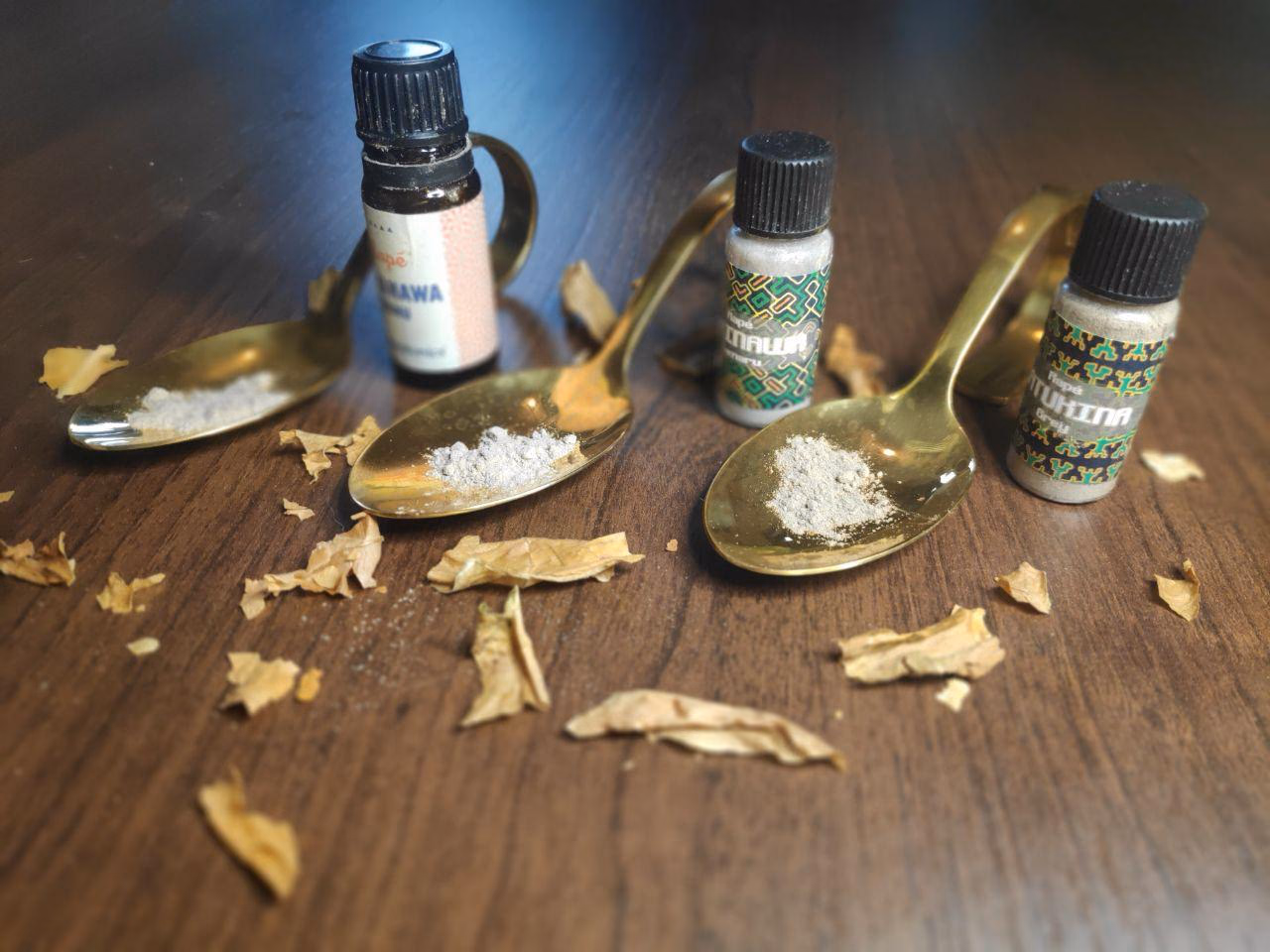 Drei Flaeschchen mit aetherischen Oelen und getrocknete Kraeuter auf einem Holztisch