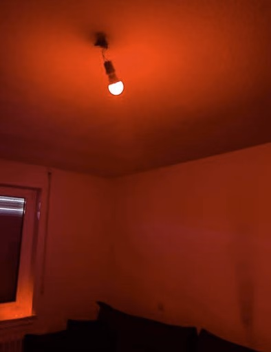 Einzelne Rotlichtlampe an der Decke eines dunklen Raumes